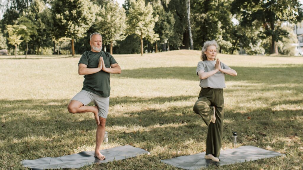Zwei ältere Erwachsene machen gemeinsam Fitnessübungen im Park.